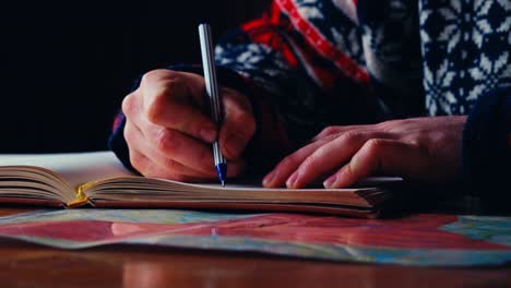 a person writes with a ballpen in a journal laid over a colorful page, capturing a quiet indoor moment of reflection or planning in reinsjøen, åfjord, norway - close-up shot