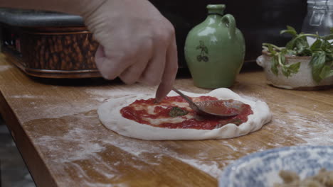 Nahaufnahme-Der-Hände-Des-Küchenchefs,-Der-Die-Pizzasauce-über-Den-Teig-Verteilt