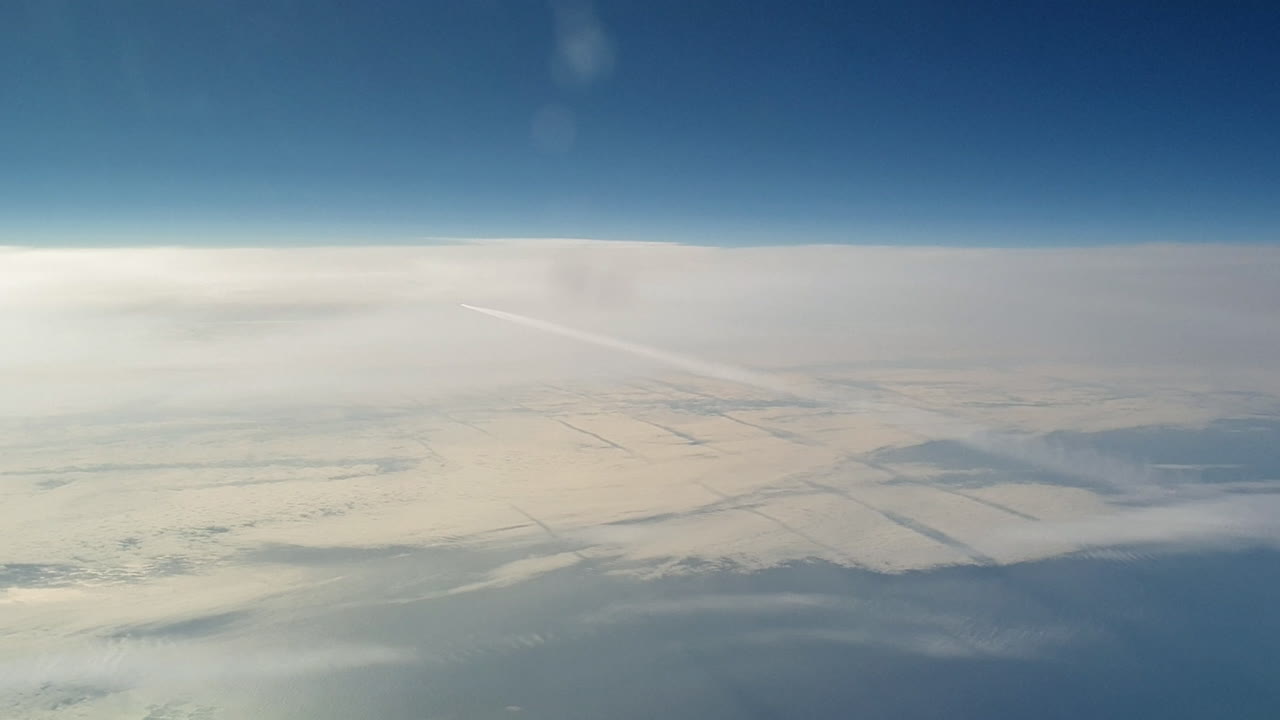 vista increíble desde la cabina de un avión que vuela alto por encima de las nubes dejando un largo rastro de aire de vapor de condensación blanco en el cielo azul