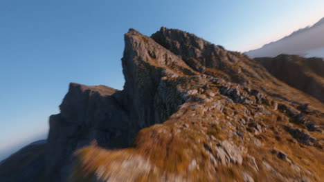 fpv drone aerial of the crest of a mountain range, lofoten islands in norway, impressive low flight