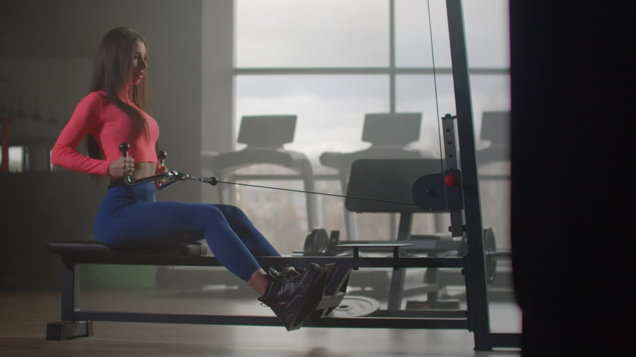 The young sportswoman is training her shoulder blades in gym. She is keeping her back straight while exercising. The pain of today is the victory of tomorrow.