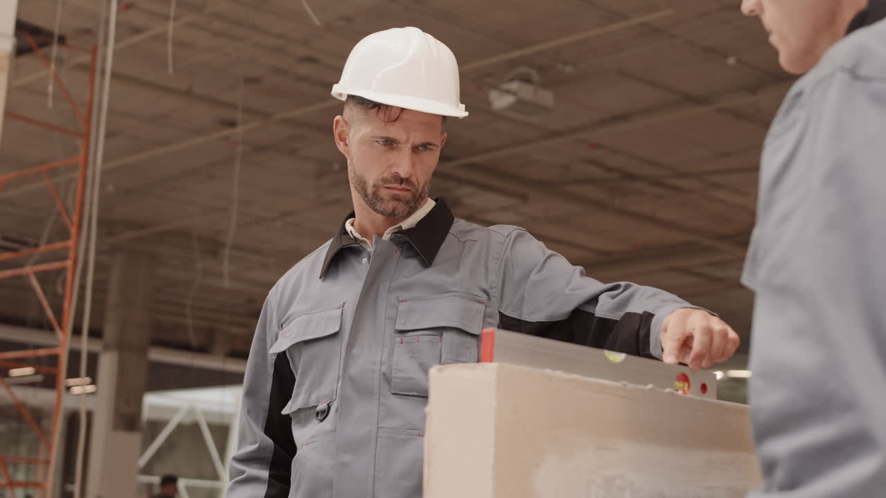 Tired Builder Looking at Spirit Level
