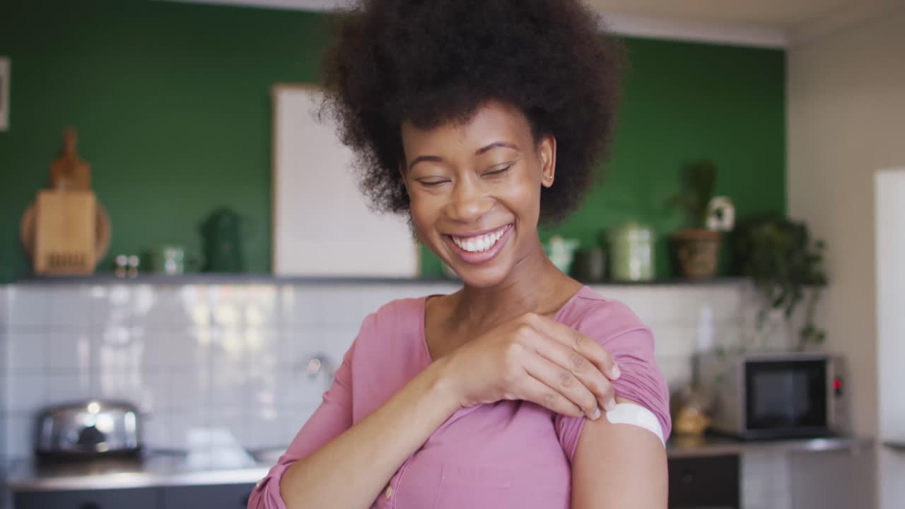 Felice donna anziana afroamericana che mostra un cerotto sul braccio dopo la vaccinazione anti-Covid.