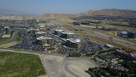 Drone-shot-over-business-park-in-Utah,-overlooking-freeway-and-mountains-in-background