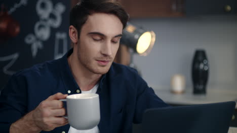 happy man having video call on laptop at home. business man drinking coffee