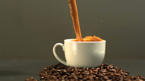 coffee being poured into cup on mound of coffee beans