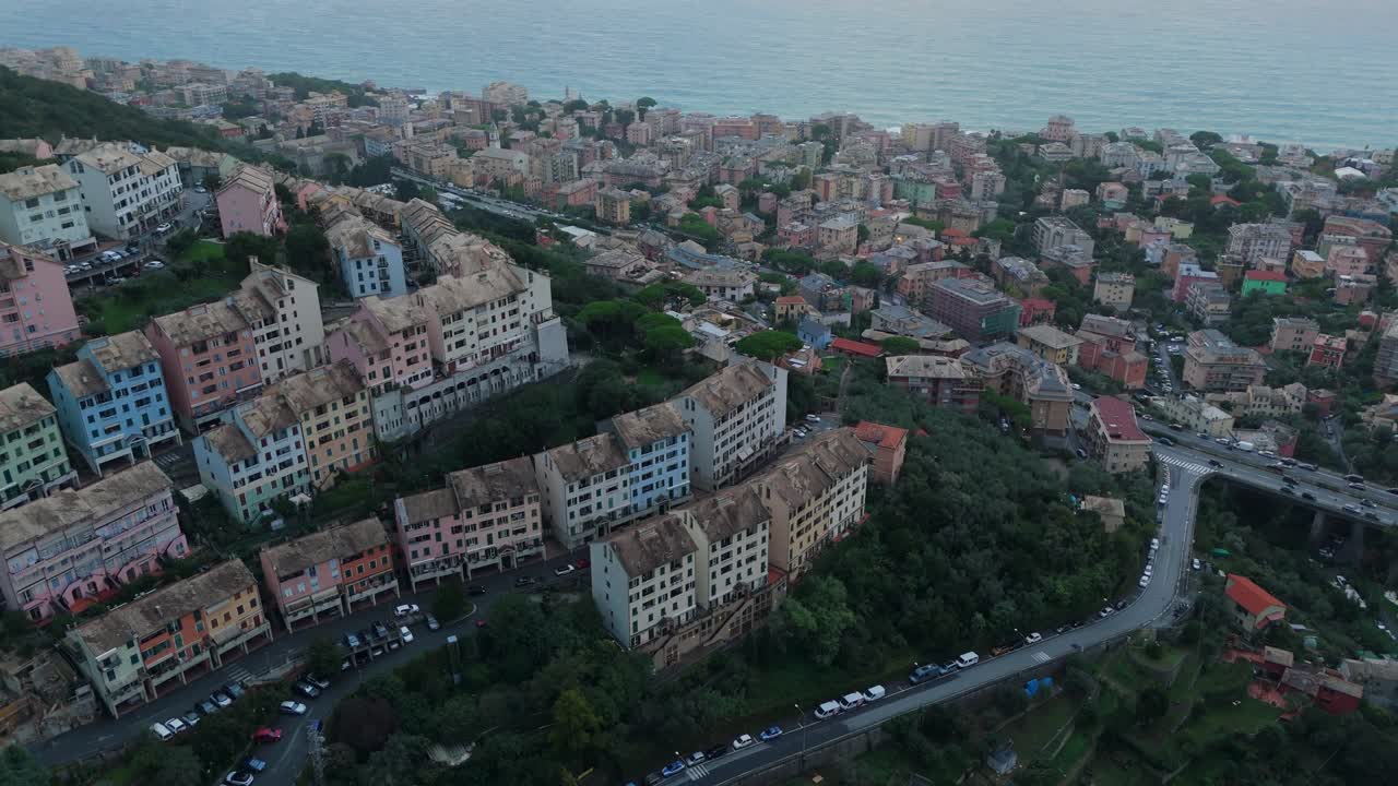 Colorful italian coastal town with hillside houses overlooking the sea at dusk, aerial view