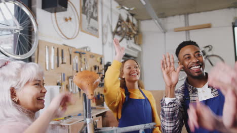 Equipo-Multicultural-De-Aprendices-En-Talleres-De-Construcción-De-Bicicletas-Dándose-Los-Cinco-Mutuamente