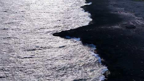 drone push in tilt down to rocky outcrop of basalt eroded by strong ocean waves crashing