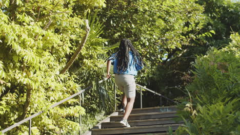 back view of african-american woman running up stairs in park