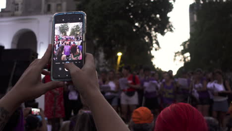 close up of woman's hands takes photo of public outdoors feminist speech during women’s day peaceful protest