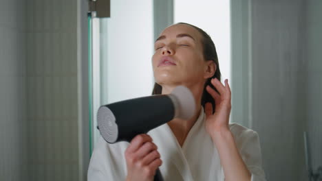 lady blowing wet hair looking camera closeup. smiling woman preparing in morning