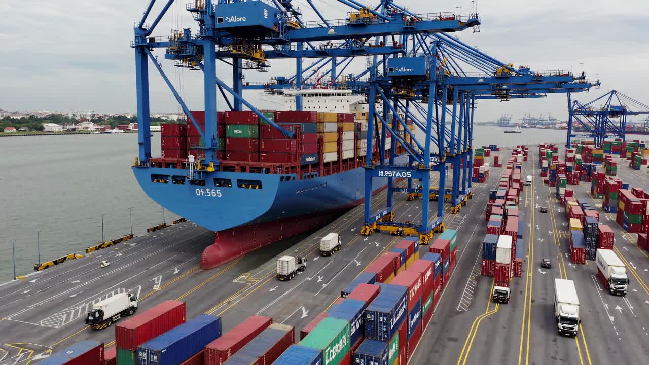 Aerial video captures a bustling port with towering cranes loading containers onto a cargo ship