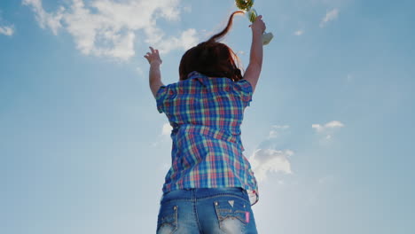 una mujer joven con una copa de campeón salta alto hacia el cielo