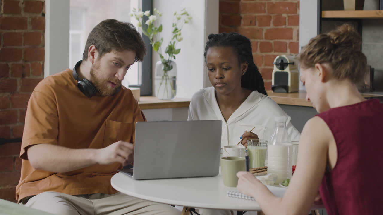 Three  Rommates Sitting Together In The Kitchen During Breakfast
