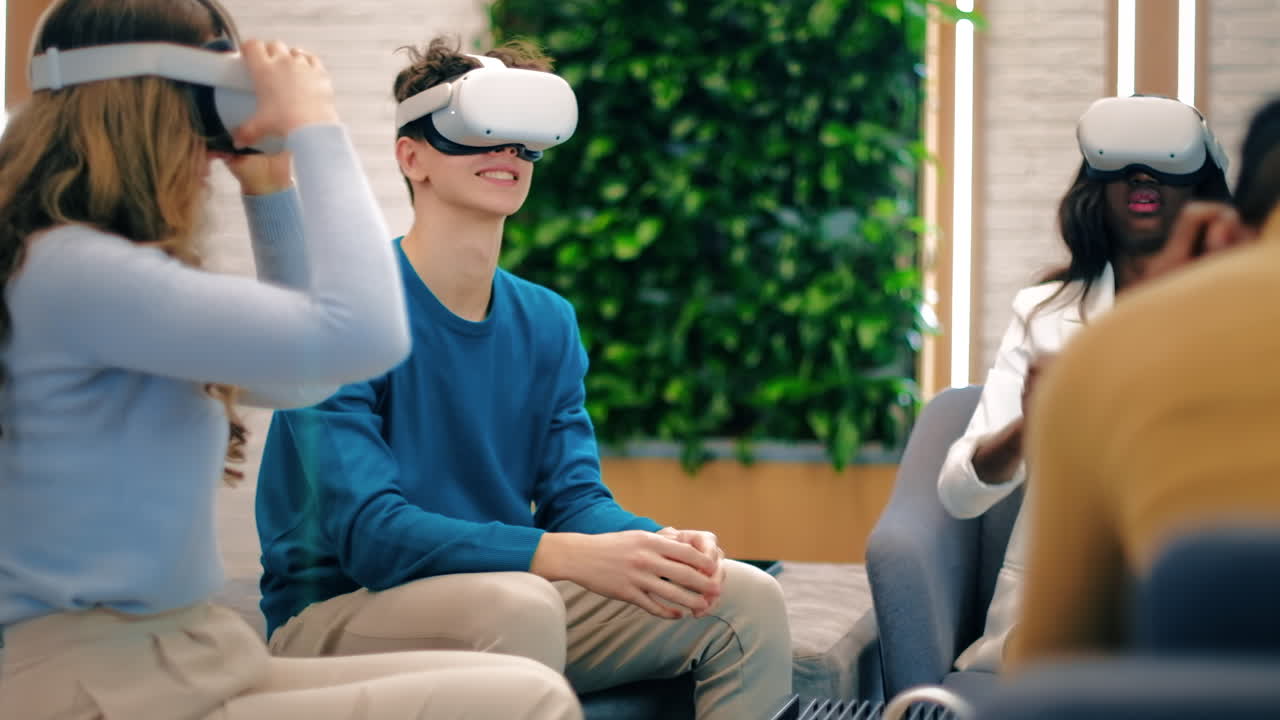 Business conference in VR in an office. Multiracial group of people. A young man teaching others how to use VR glasses and controllers