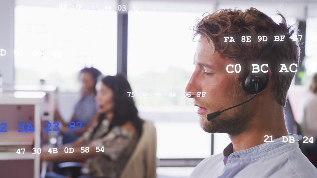 Male call center agent taking call speaking into headset team typing hex codes floating over agents