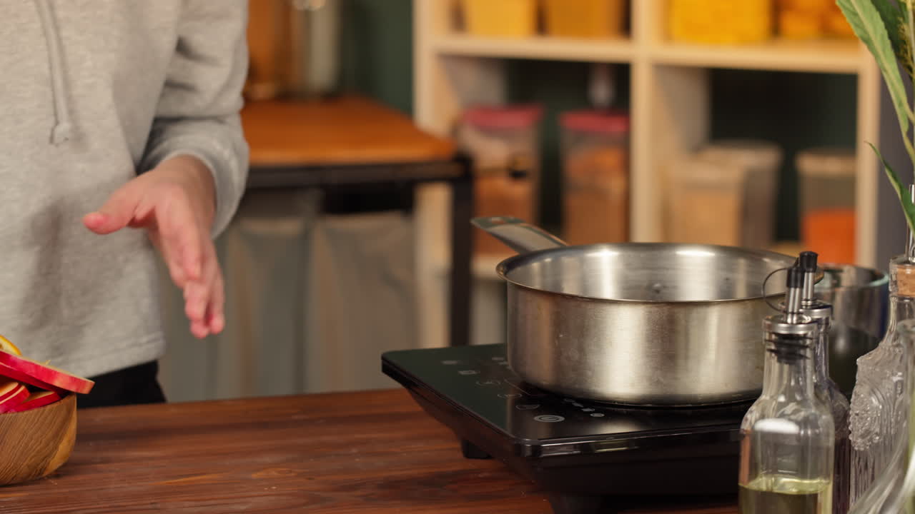 Persona vertiendo vino tinto y añadiendo rodajas de fruta a una olla