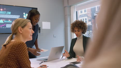 Joven-Empresaria-Liderando-Una-Reunión-Creativa-De-Mujeres-Que-Colaboran-Alrededor-De-Una-Mesa-En-Una-Oficina-Moderna