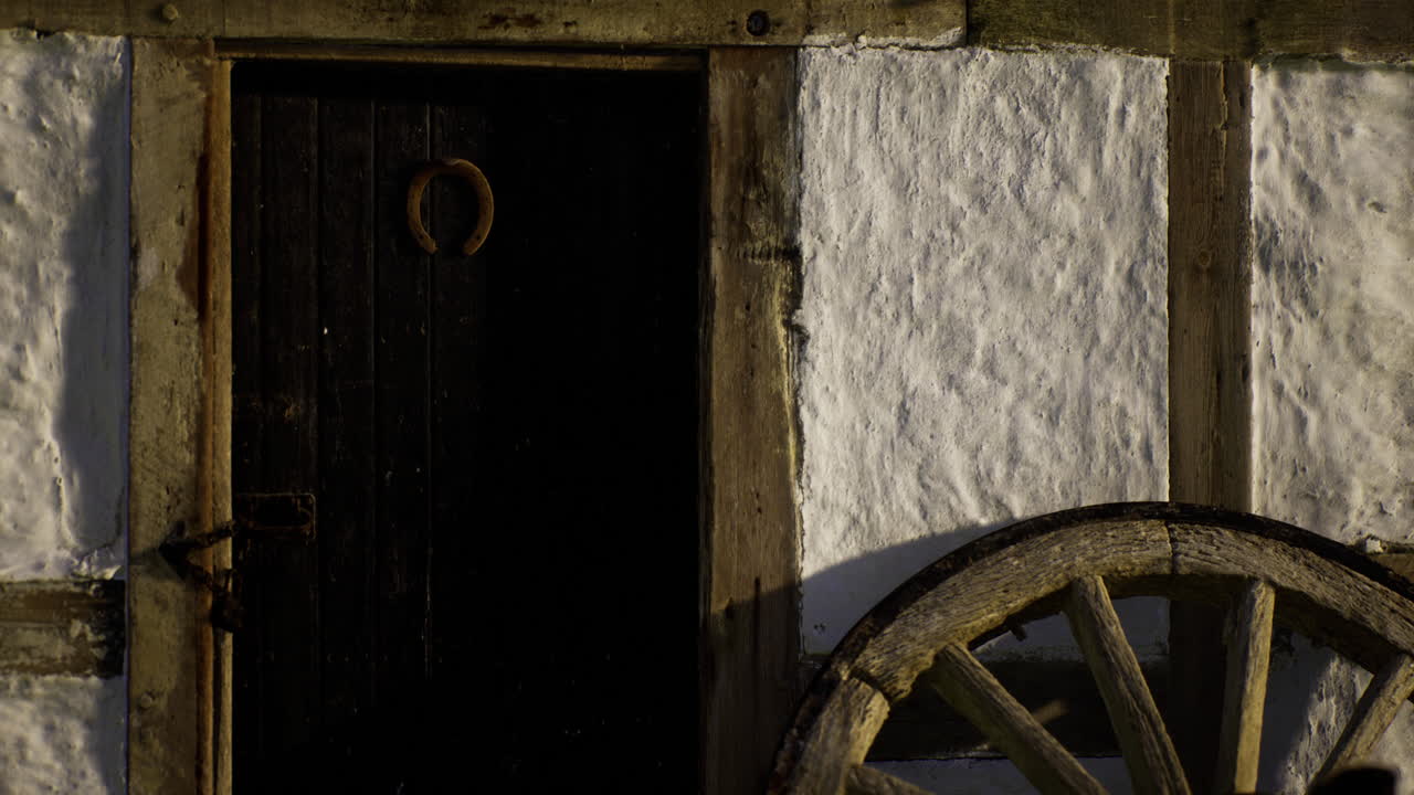 Rustic wooden wheel next to an old door reveals village charm at sunset