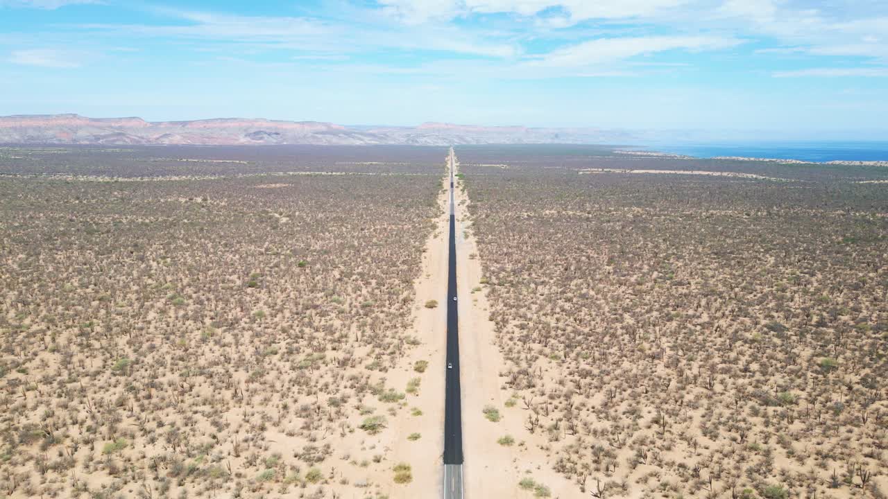 Lonely desert road stretching into the horizon near La Paz, Mexico, surrounded by barren land