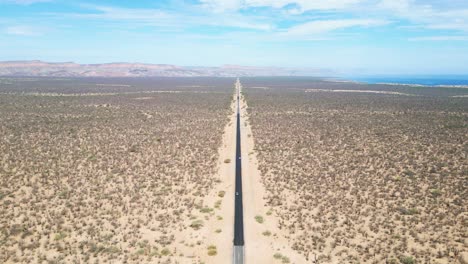 lonely desert road stretching into the horizon near la paz, mexico, surrounded by barren land