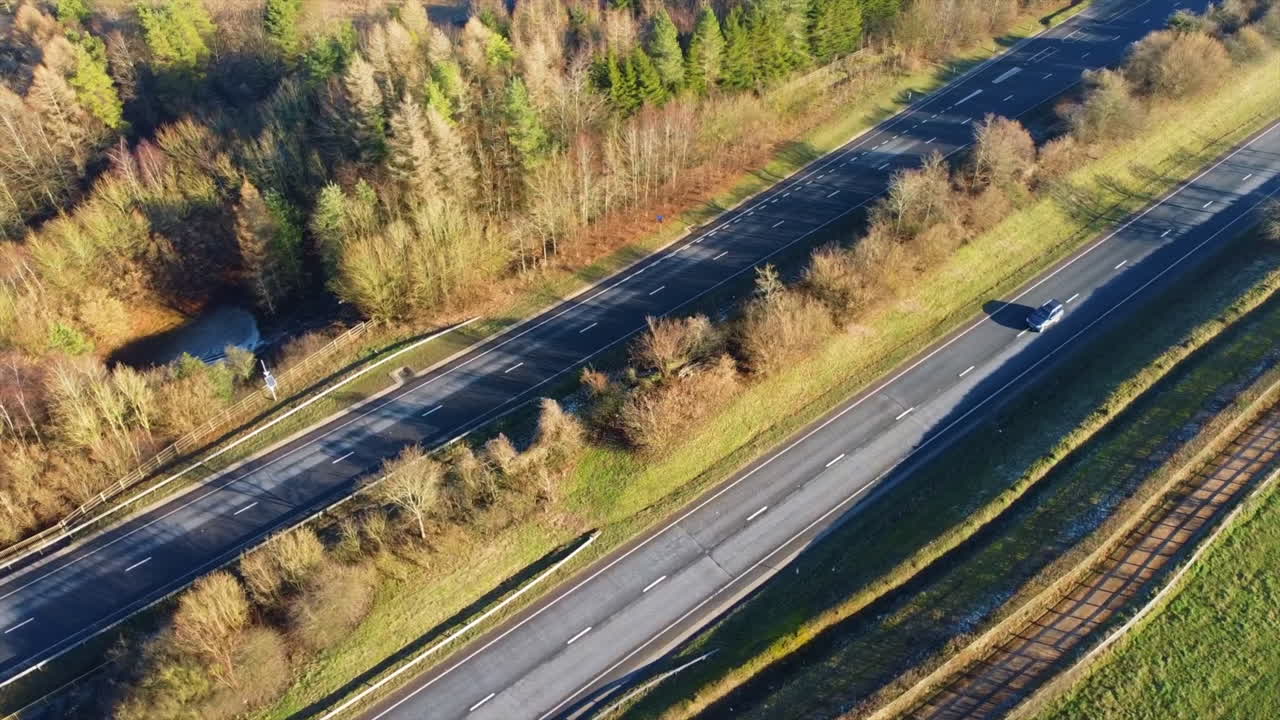 Aerial view of cars driving on the highway near trees and agricultural land