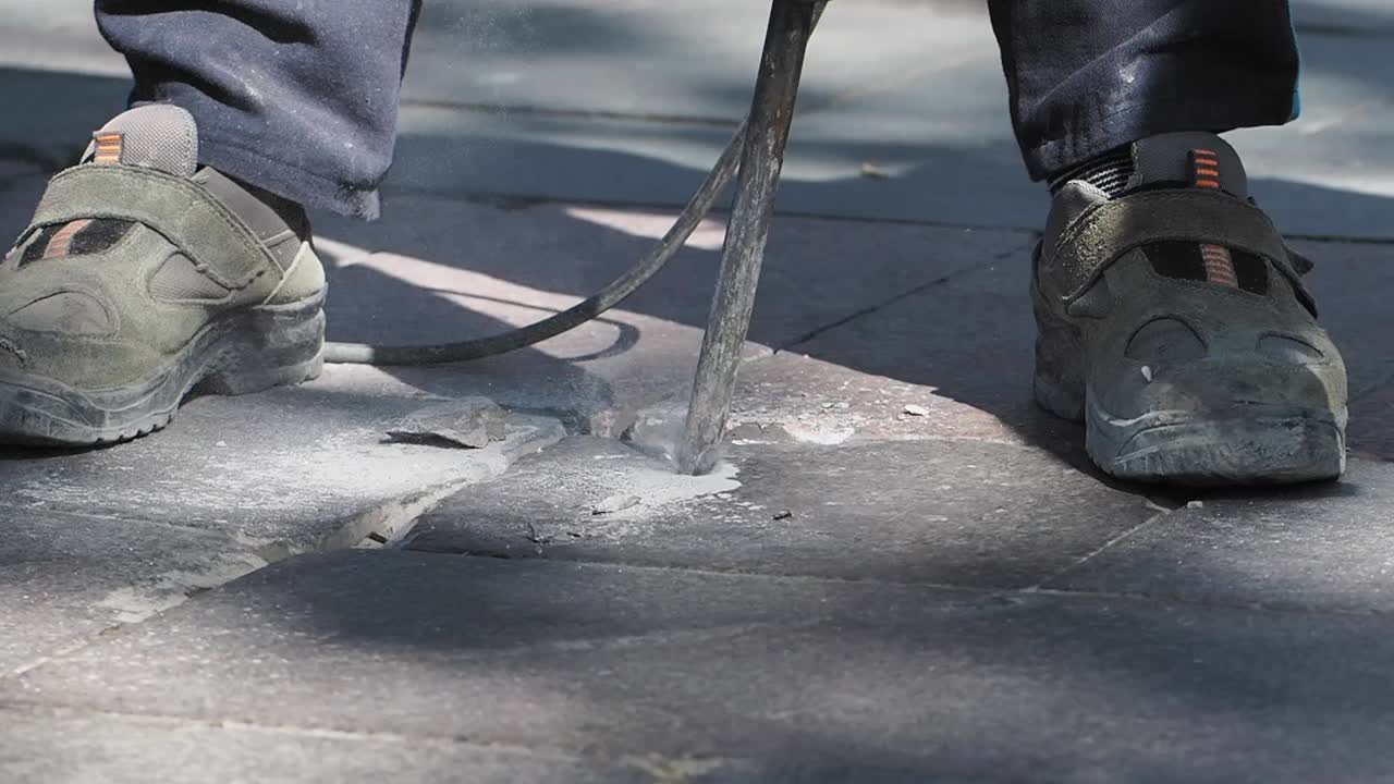 Close-up of a worker using a jackhammer to break pavement