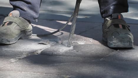 close-up of a worker using a jackhammer to break pavement