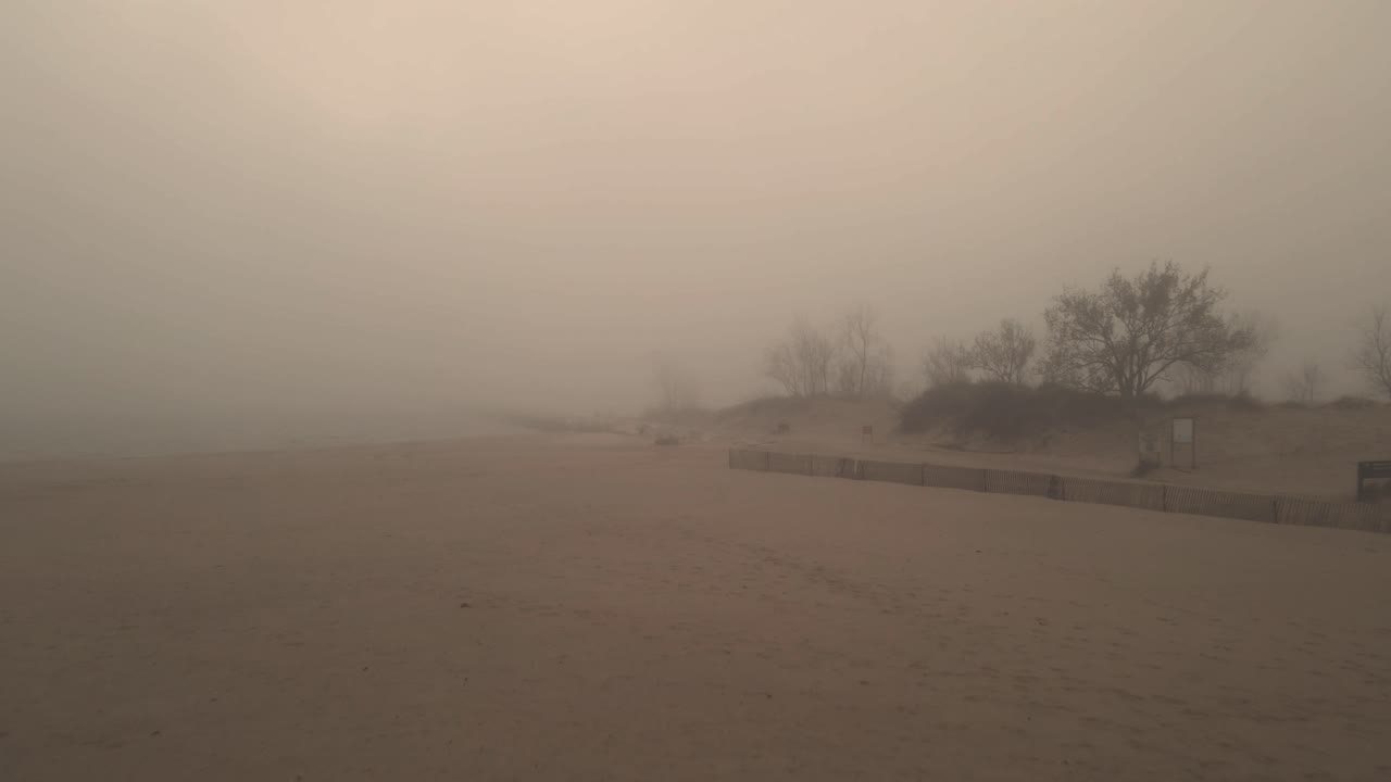 un paseo marítimo de piedra distante apenas visible a través de la densa niebla de la playa