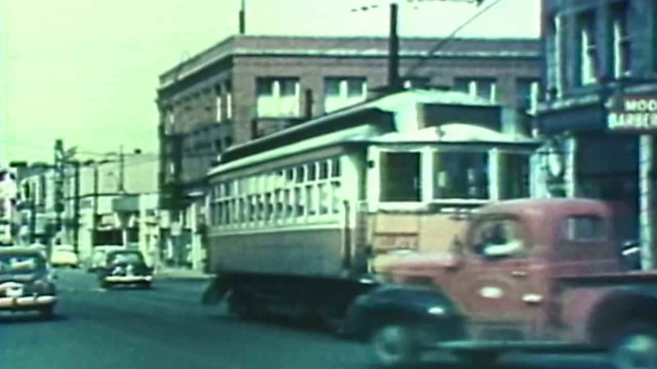 1950S STREETCAR IN DOWNTOWN PORTLAND OREGON WHILE CARS DRIVE NEARBY