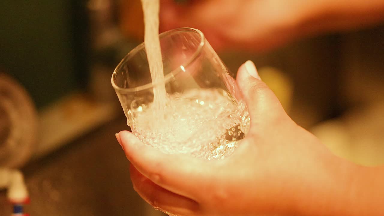 손 은 흐르는 물 으로 유리잔 을 청소 하고 있다