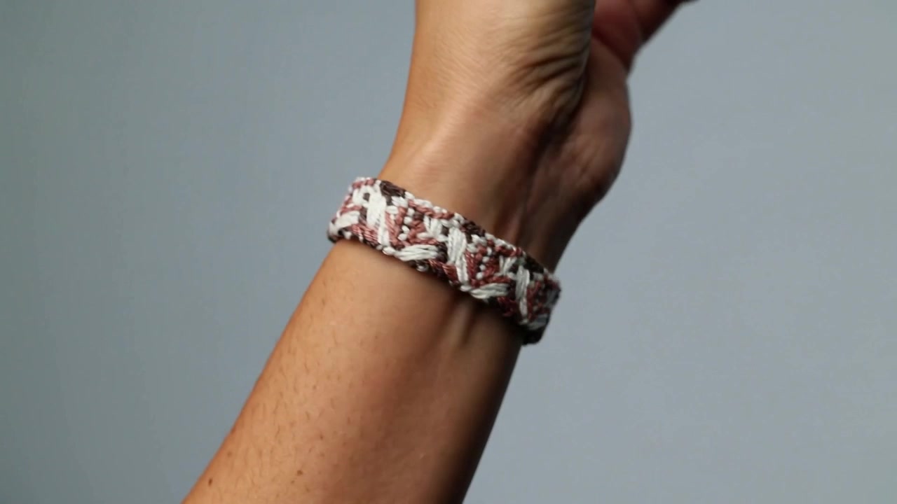 Rotating wrist revealing woven macrame bracelet on studio grey backdrop, showing clasp for display