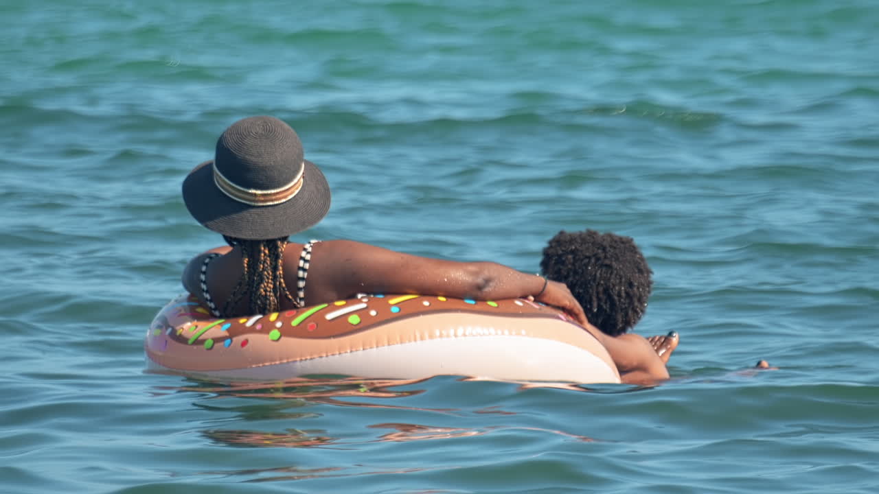 Two people chilling on a rubber ring in a sea
