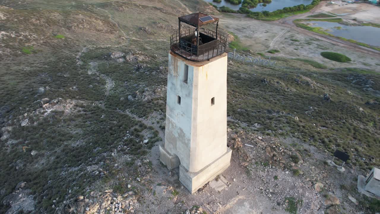 An aerial view of an old lighthouse in Gran Roque, Los Roques, surrounded by rugged terrain