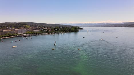 Drone-flyover-shot-over-lake-Zürich-in-Switzerland-towards-chinese-garden-on-a-hot-summer-day