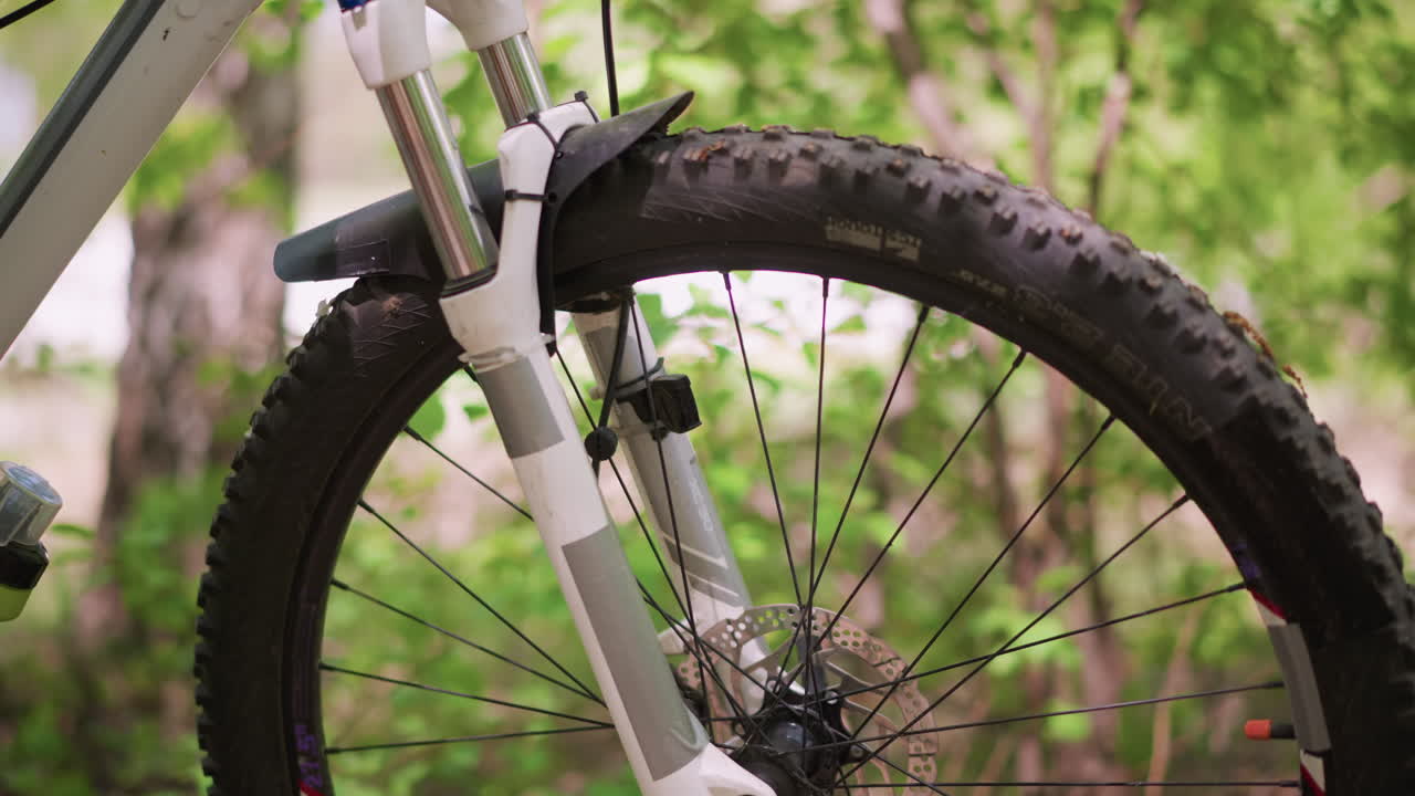 Forest Trail Scene With Bike Wheel, Suspension Fork And Knobby Tire On Mountain Bike, Detailed View Of Mountain Bike Front Wheel With Textured Tire And Suspension In Forest Setting