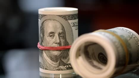 Cash-money-rolls-on-table.-Rotating-rolls-of-hundred-american-dollar-bills