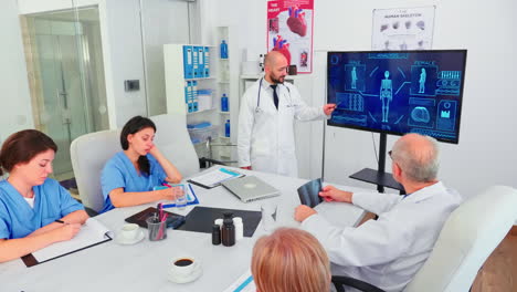 experto médico hablando sobre atención médica apuntando a un monitor digital