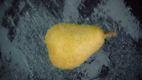 pera con salpicaduras de agua clara sobre un fondo negro. super bucle de cámara lenta.