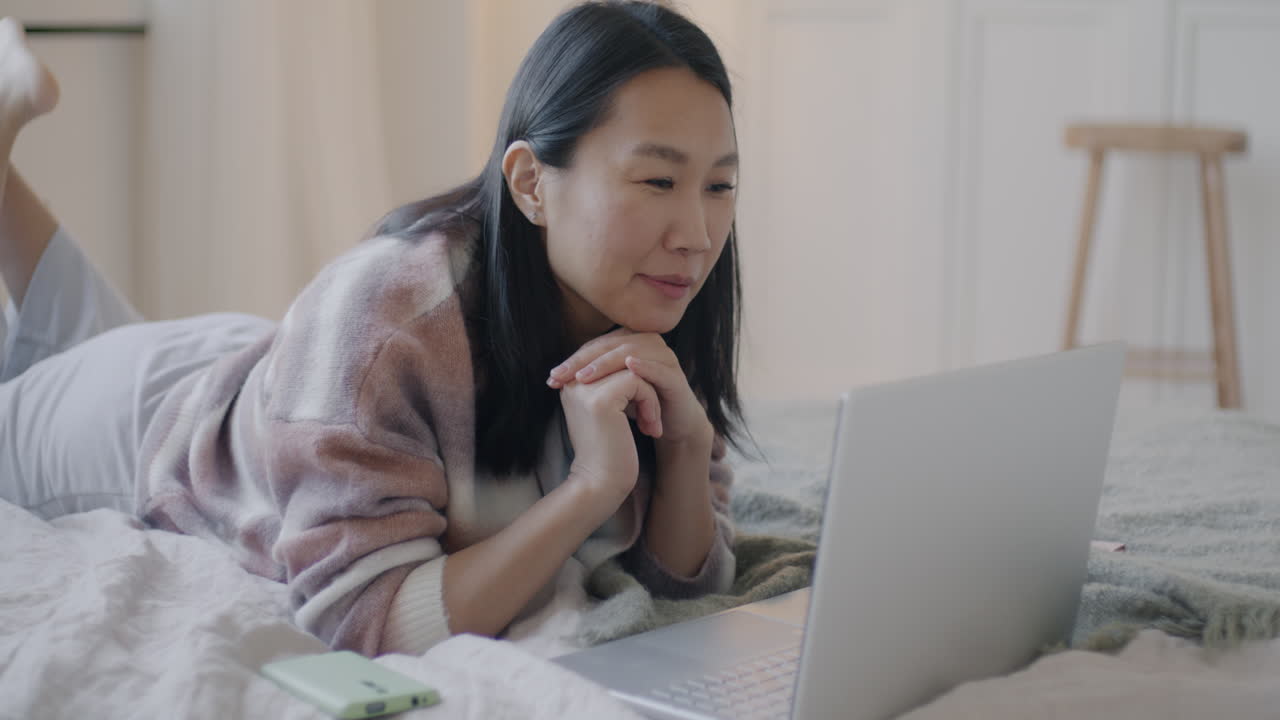 침대에 노트북으로 일하는 여자