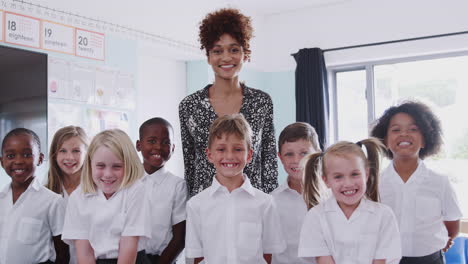 portrait of elementary school pupils wearing uniform in classroom with male teacher