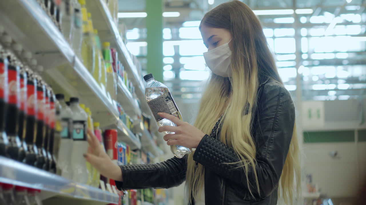 mujer comprando agua en una tienda de comestibles con una máscara facial