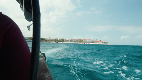 boat view of stone town's coastline and choppy turquoise waters