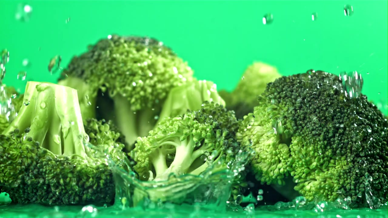 Cimette di broccoli freschi con schizzi d'acqua su sfondo verde