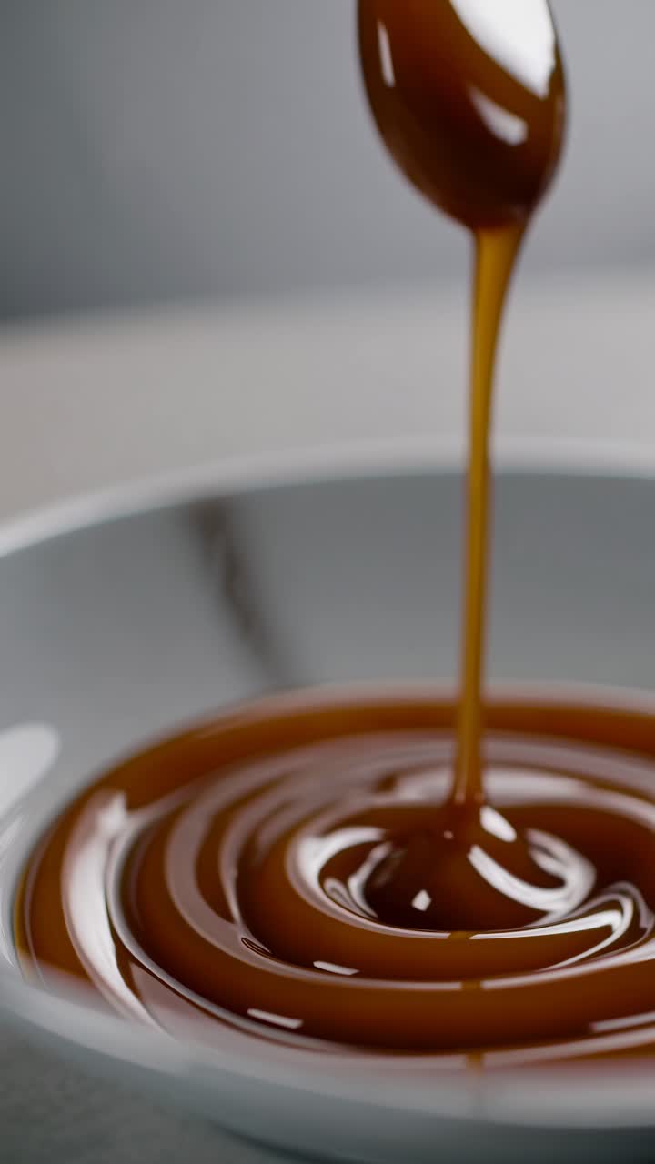 Video ravvicinato di sciroppo che cola elegantemente da un cucchiaio in una ciotola