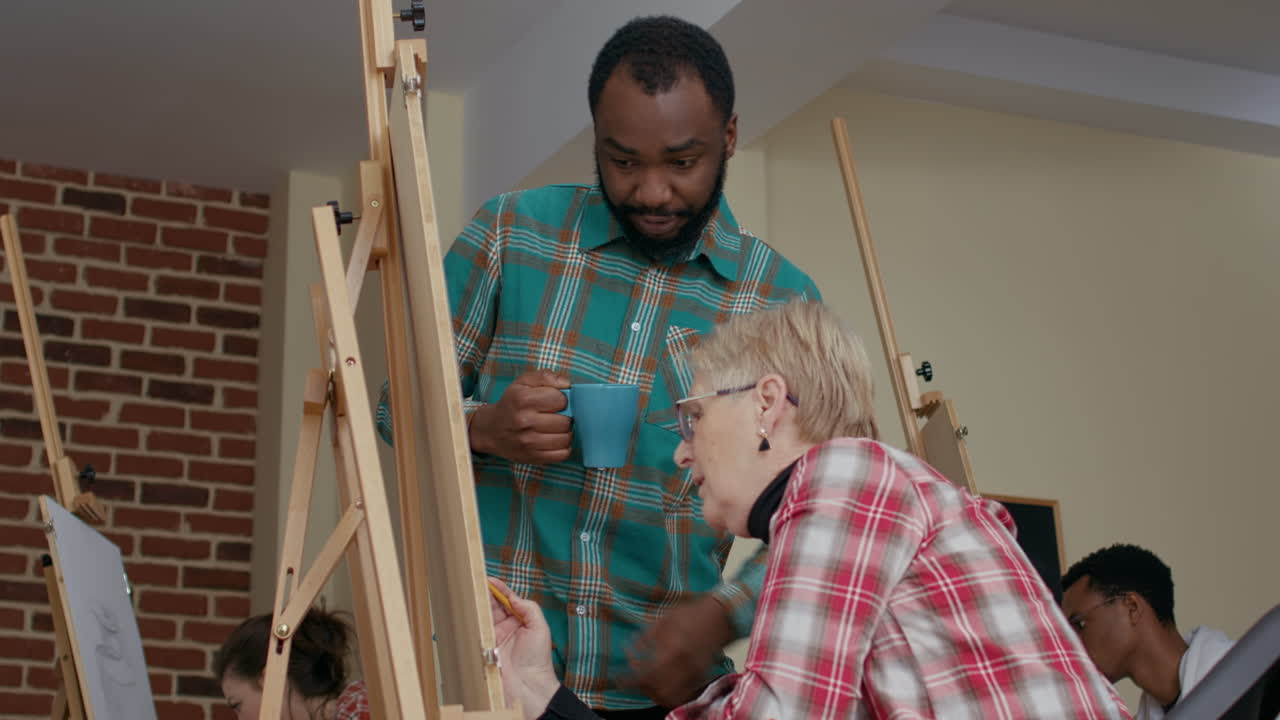 African american teacher guiding senior woman to draw sketch