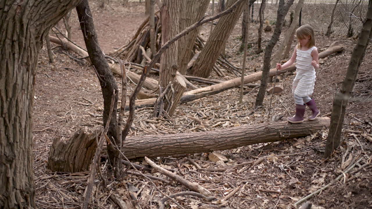 Little girl balancing on a log in the forest
