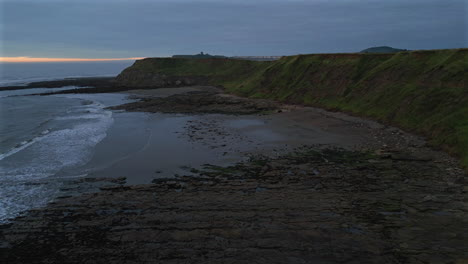 establishing aerial drone shot of cleveland way on misty morning at low tide in scarborough