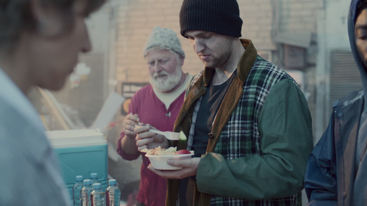 Homeless Men Receiving Hot Meals from Volunteers at Food Station in Back Alley